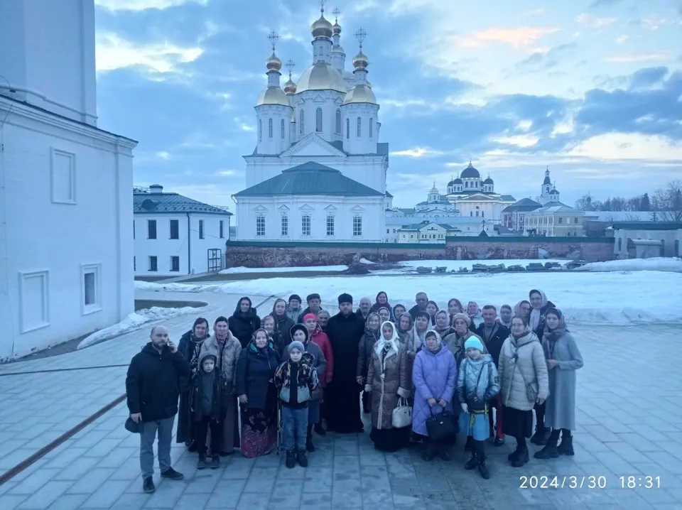 Группа паломников на фоне белого собора с золотыми куполами