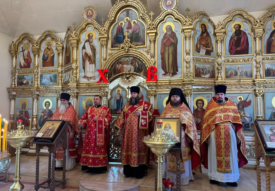 Духовенство в красных облачениях служит у золочёного иконостаса