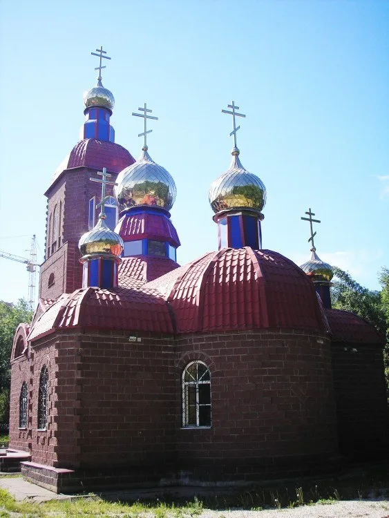 Пять золотых куполов на красных кровлях храма на фоне синего неба