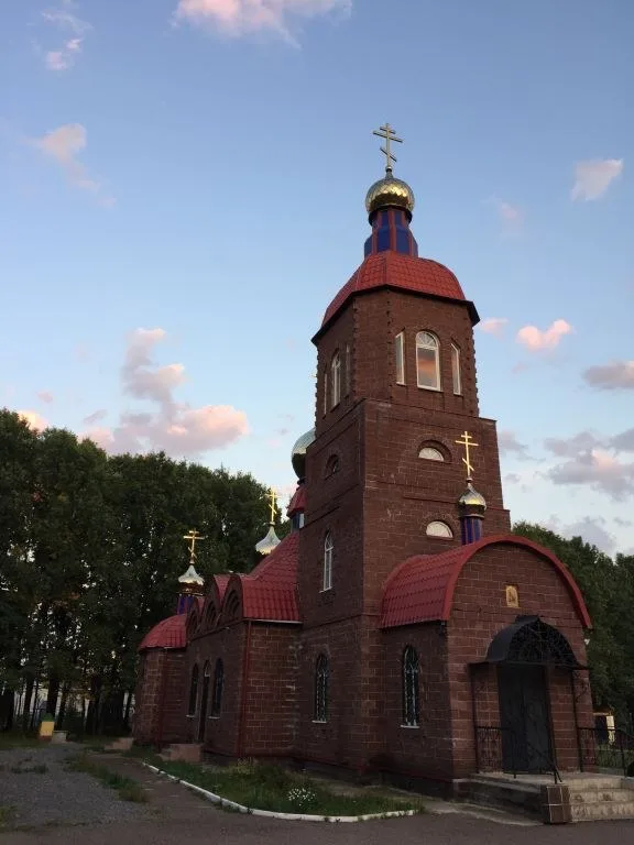 Кирпичный храм с золотыми куполами на фоне вечернего неба